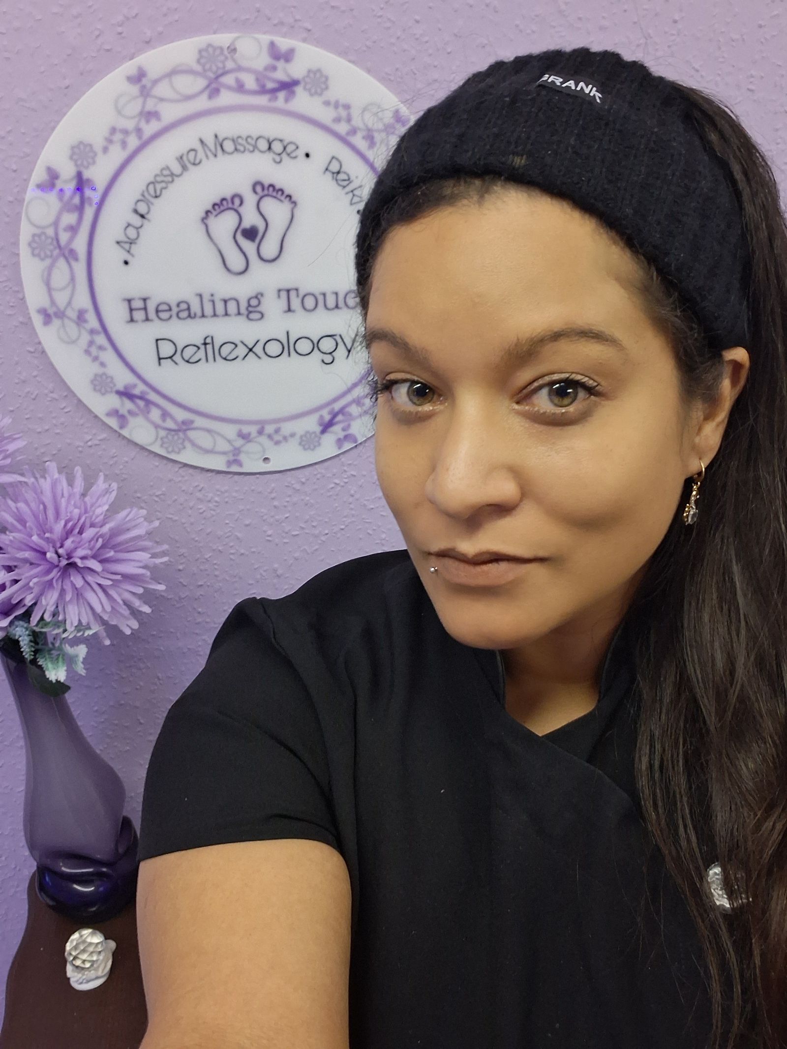 Elle Bussey in her treatment room beside the Healing Touch Reflexology sign