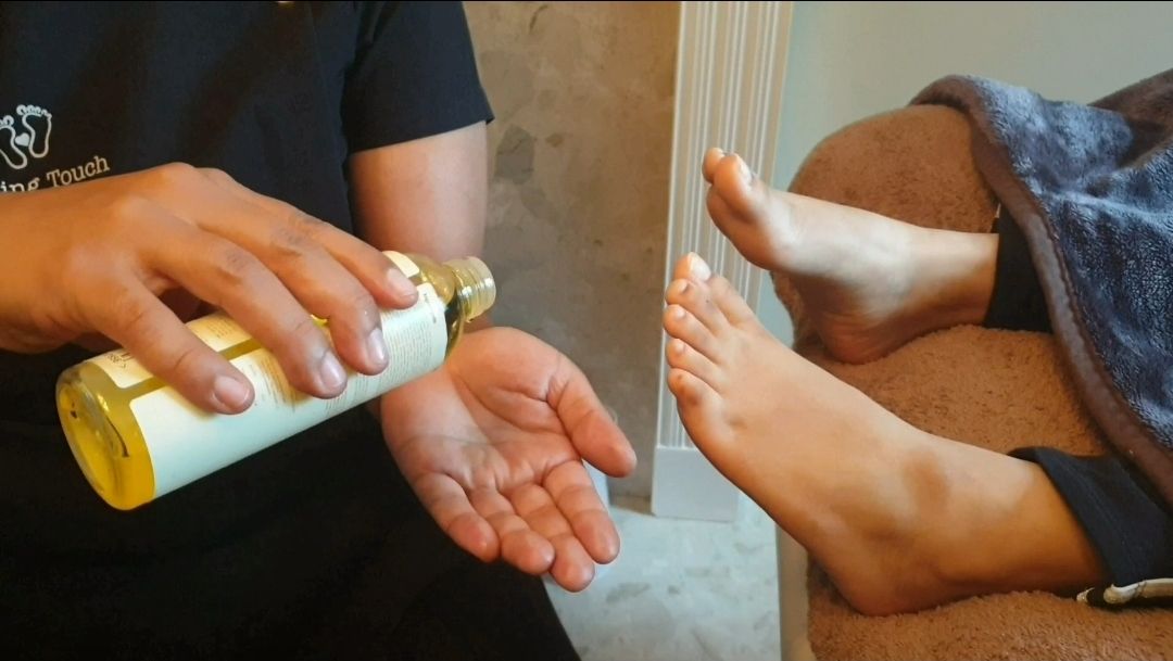 Oil being poured into a hand before a foot treatment
